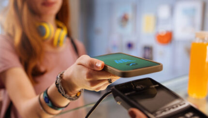 Nastolatek dokonujący płatności smartfonem przy terminalu płatniczym w sklepie